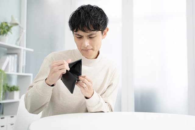 財布の中を見て落胆する男性